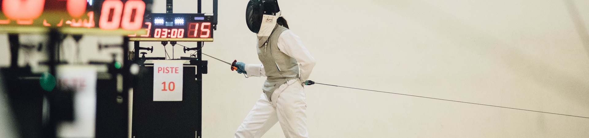 A fencer walks forward while attached to a tether used for scoring.