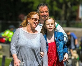 At the Carroll Center for the Blind's Walk for Independence, a family of three walk up the driveway laughing in the sunshine.