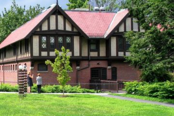 A view across the sprawling green lawn of the Carroll Center for the Blind's main building, a large Tudor-style brick structure.