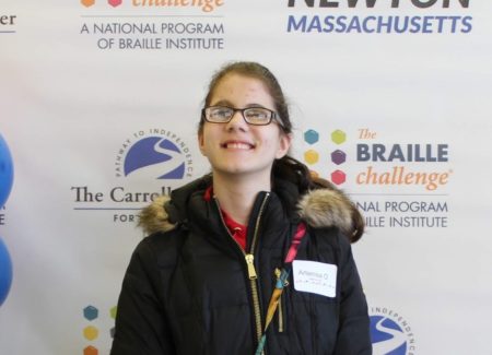 Standing in front of a red-carpet style backdrop, top scorer in the “Sophomore” category, Artenisa Osmani, smiles.