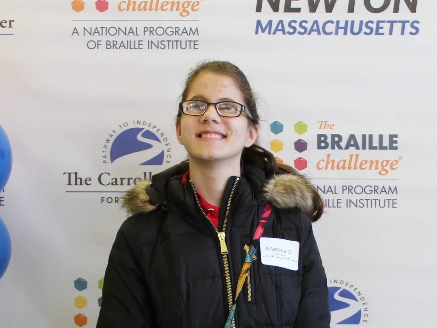 Standing in front of a red-carpet style backdrop, top scorer in the “Sophomore” category, Artenisa Osmani, smiles.