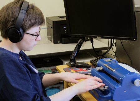 Focused on typing with her perkins brailler, top scorer in the “Varsity” category, Kelly Cusack, listens to the prompt during the Braille Challenge.