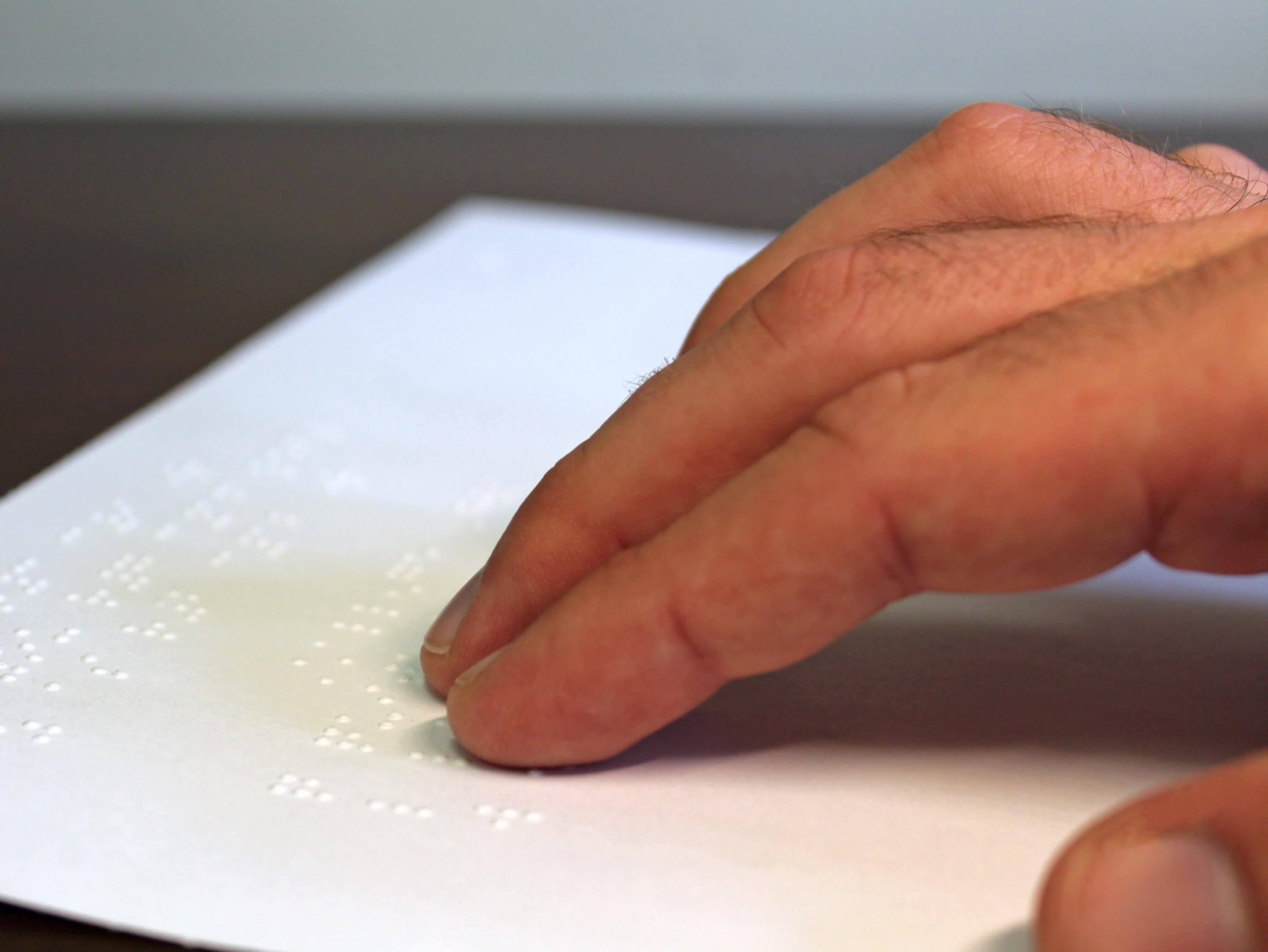 A man reads a braille sheet.