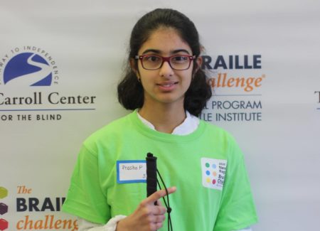Sophomore group winner, Prasha Parajuli, poses in front of a braille challenge banner while wearing a green braille challenge shirt.