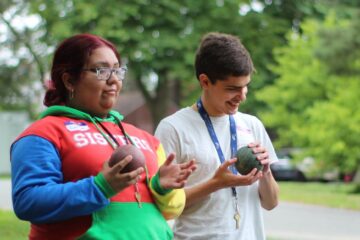 On field day, two youth in transition students laugh as they play Bocce.