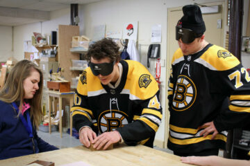In the Carroll Center's manual arts shop, Tuukka Rask and Frank Vatrano of the Boston Bruins explore a tactile map while occluded.