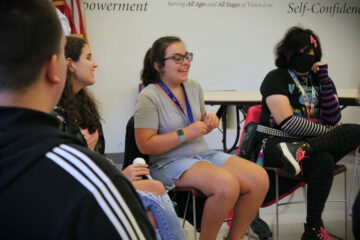 During icebreakers, a group of youth in transition summer program students sit around a circle in the technology center auditorium at the Carroll Center for the Blind.
