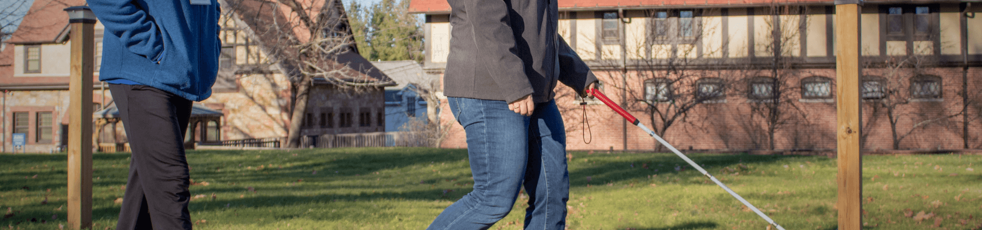 A woman walks along the driveway with her white cane at the Carroll Center for the Blind.