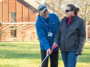 A woman laughs with her mobility instructor at the Carroll Center