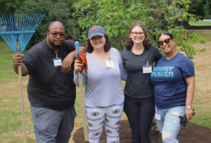 Four volunteers from Warby Parker take a break from their duties around campus to pose for a picture on the Carroll Center's front lawn.