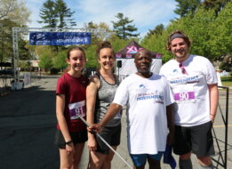 Carroll Center client standing and smiling at the Carroll Center Walk for Independence finish line with three other walk participants.