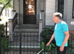 Gary is pictured walking with his white cane on the sidewalk near his home.