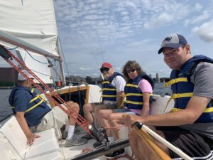 4 SailBlind program members smiling for a picture while sailing on a boat