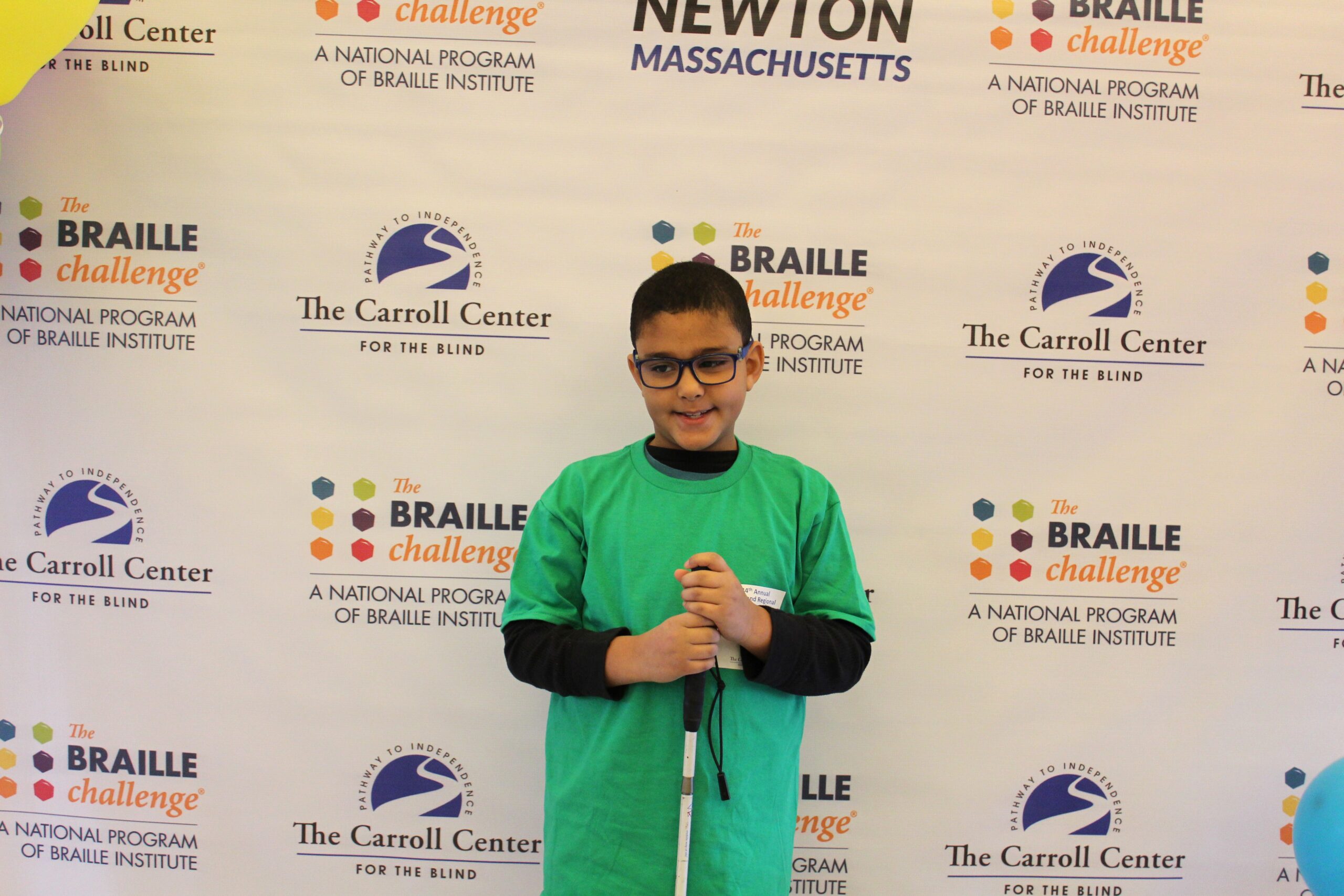 Braille Challenge participant smiling for a photo in front of the Carroll Center Braille Challenge backdrop