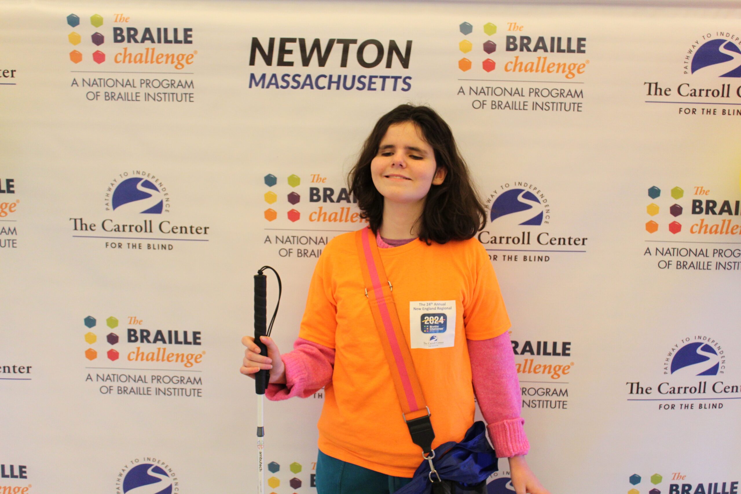 Braille Challenge participant smiling for a photo in front of the Carroll Center Braille Challenge backdrop