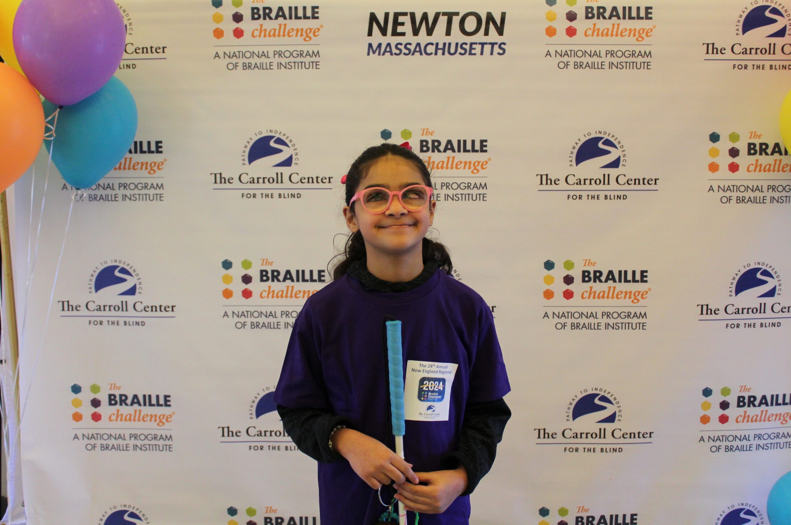 Braille Challenge participant smiling for a photo in front of the Carroll Center Braille Challenge backdrop