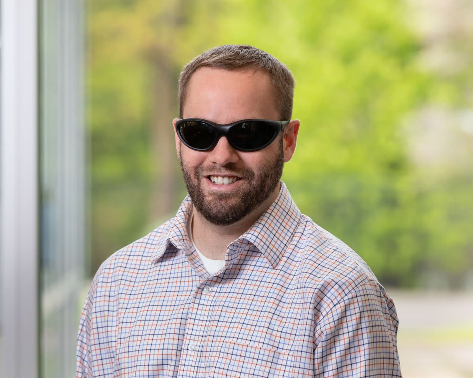 Headshot of Brian Switzer. He is a white man with short brown hair and is wearing dark glasses.