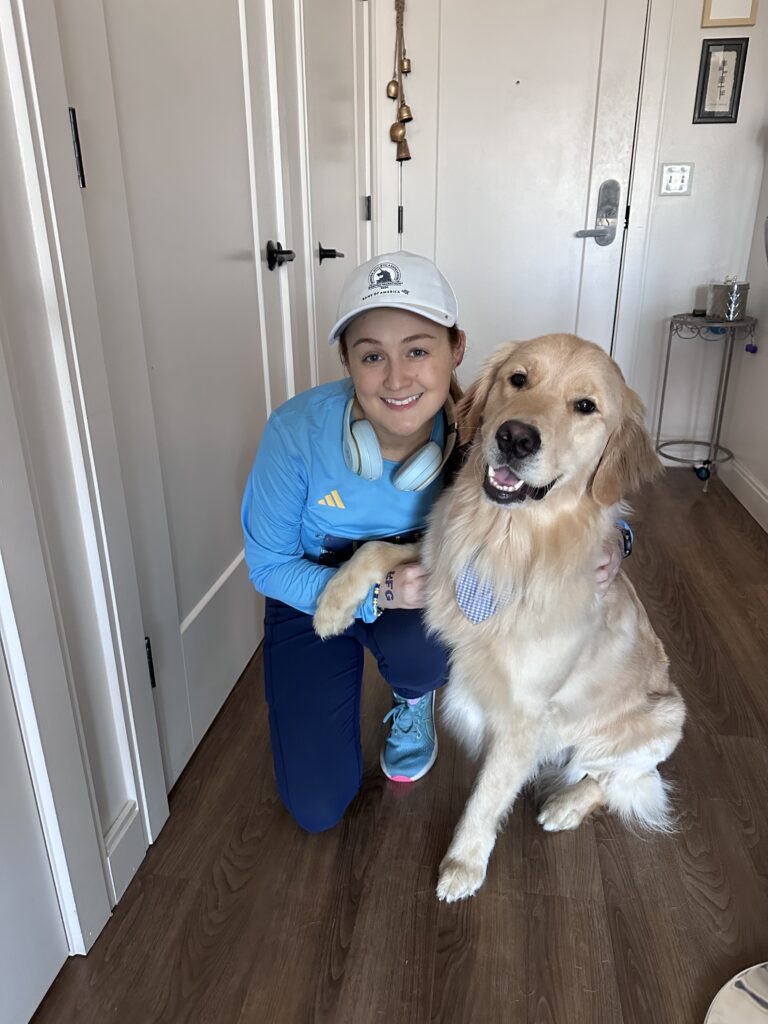 Lily Mcdonagh kneeling down to pose for a photo at her house with her golden retriever.